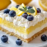 Lemon Cream Cheese Dump Cake Served In A White Baking Dish, Topped With Powdered Sugar And Garnished With Lemon Slices
