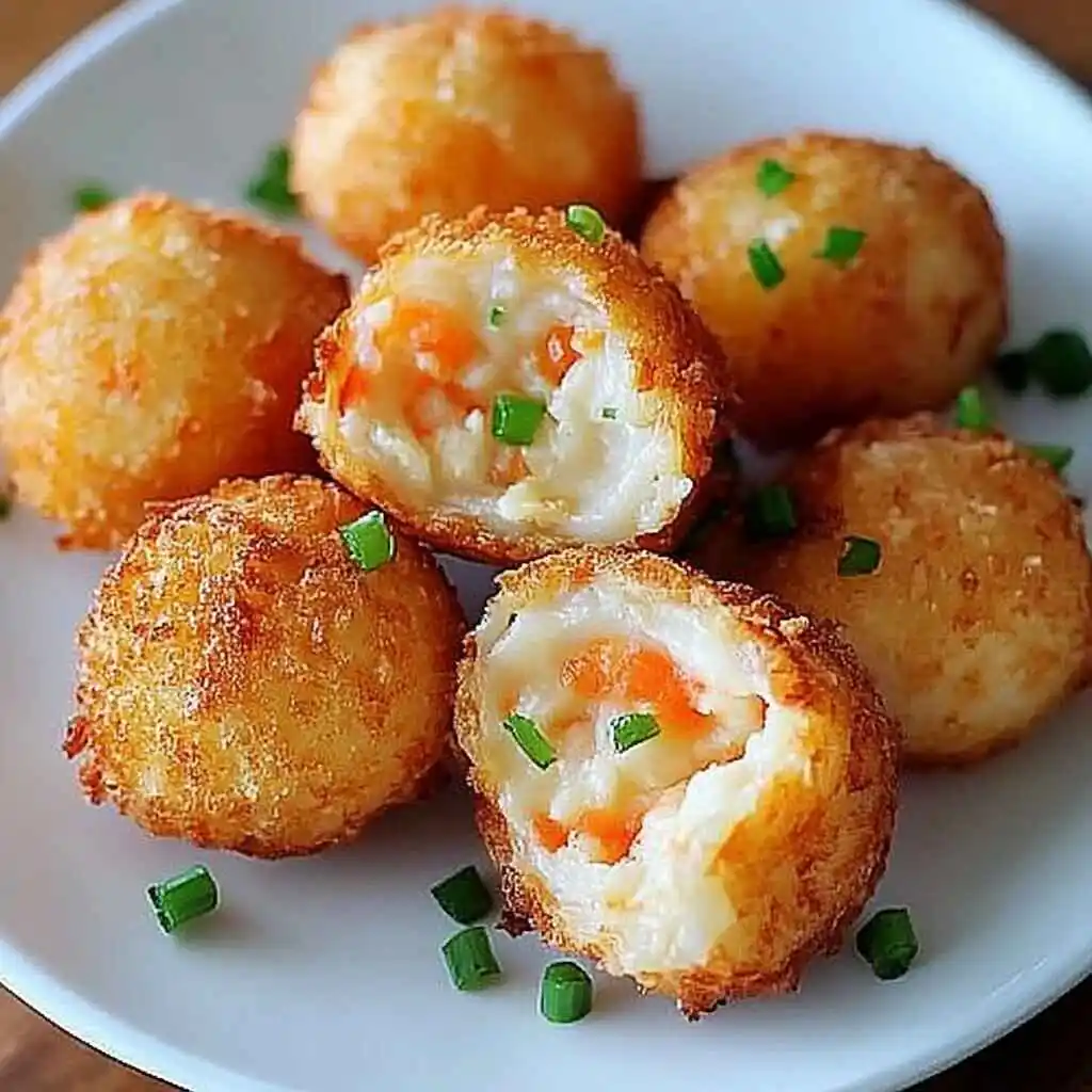Crispy Shrimp And Potato Balls, Perfectly Golden, Garnished With Fresh Chives And Served On A White Plate
